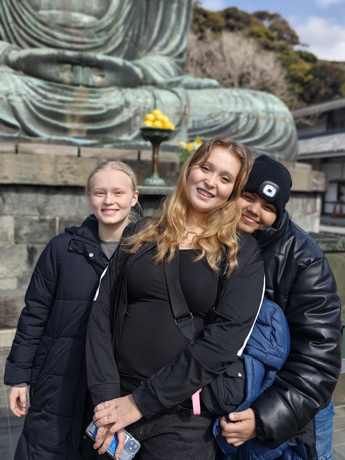 Tre glade elever foran den store Buddha statue i Kamakura – fællesskab og kulturelle oplevelser på studietur til Japan
