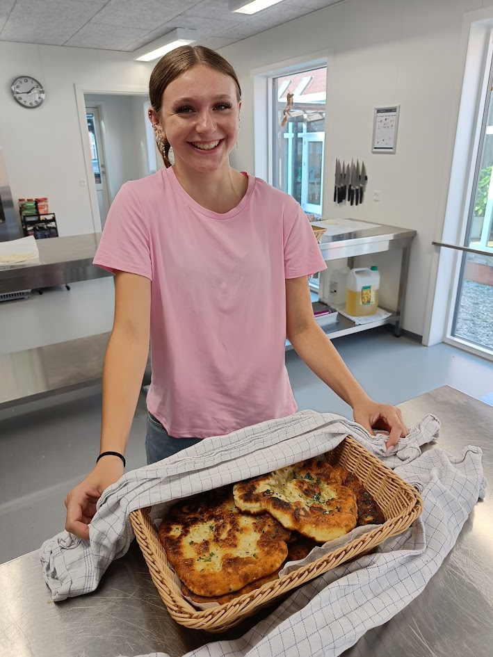 Smilende elev præsenterer friskbagt brød – undervisning i bagning og madlavning på efterskole